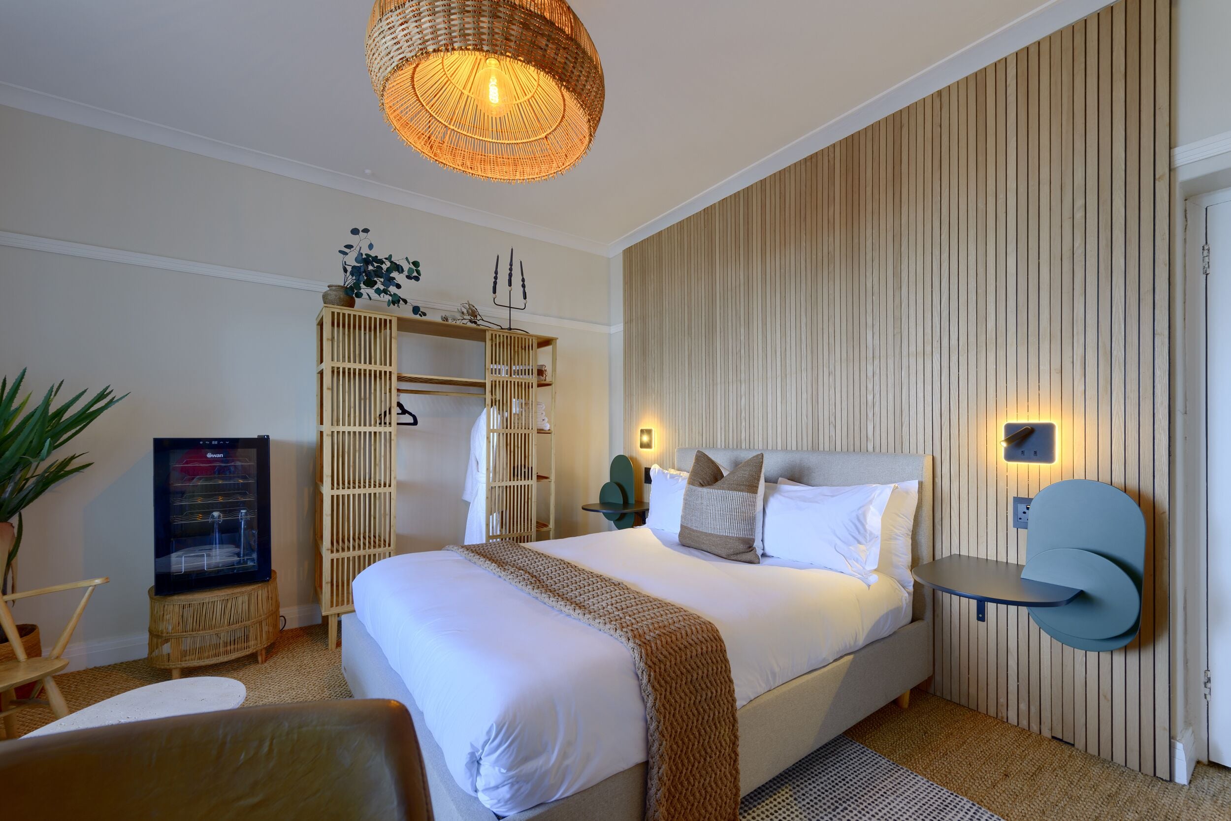 Een moderne hotelkamer met een groot bed, een televisie, een kledingkast en een nachtkastje.