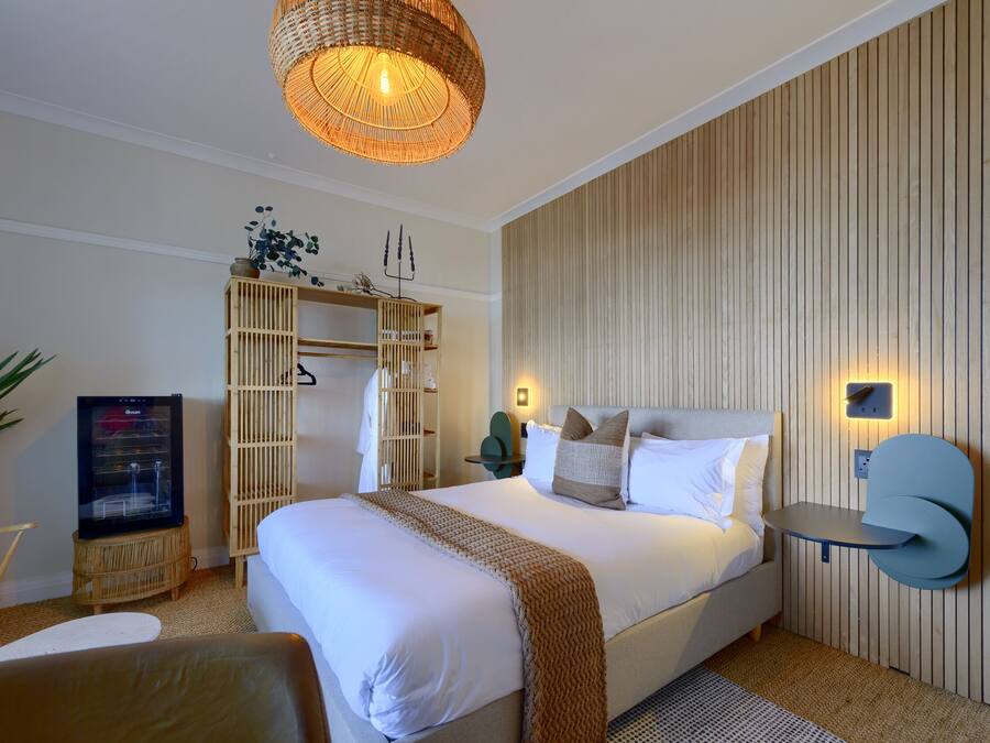 Een moderne hotelkamer met een groot bed, een televisie, een kledingkast en een nachtkastje.