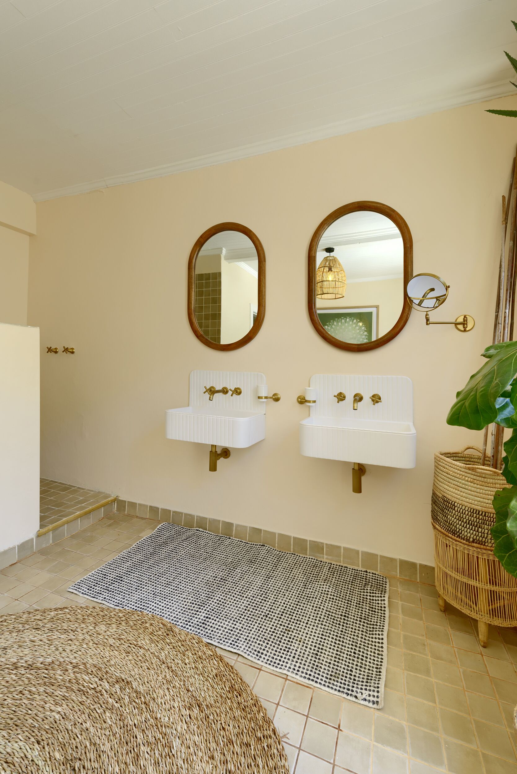 Uma casa de banho com duas lavatórios, um espelho e um tapete tecido no chão.