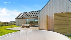 A modern house with a large deck, a hot tub, and a wooden fence. - 5 Star Holiday Home in Lokken (Lokken)