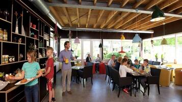 Un restaurante con vigas de madera, conductos metálicos y lámparas colgantes de colores.