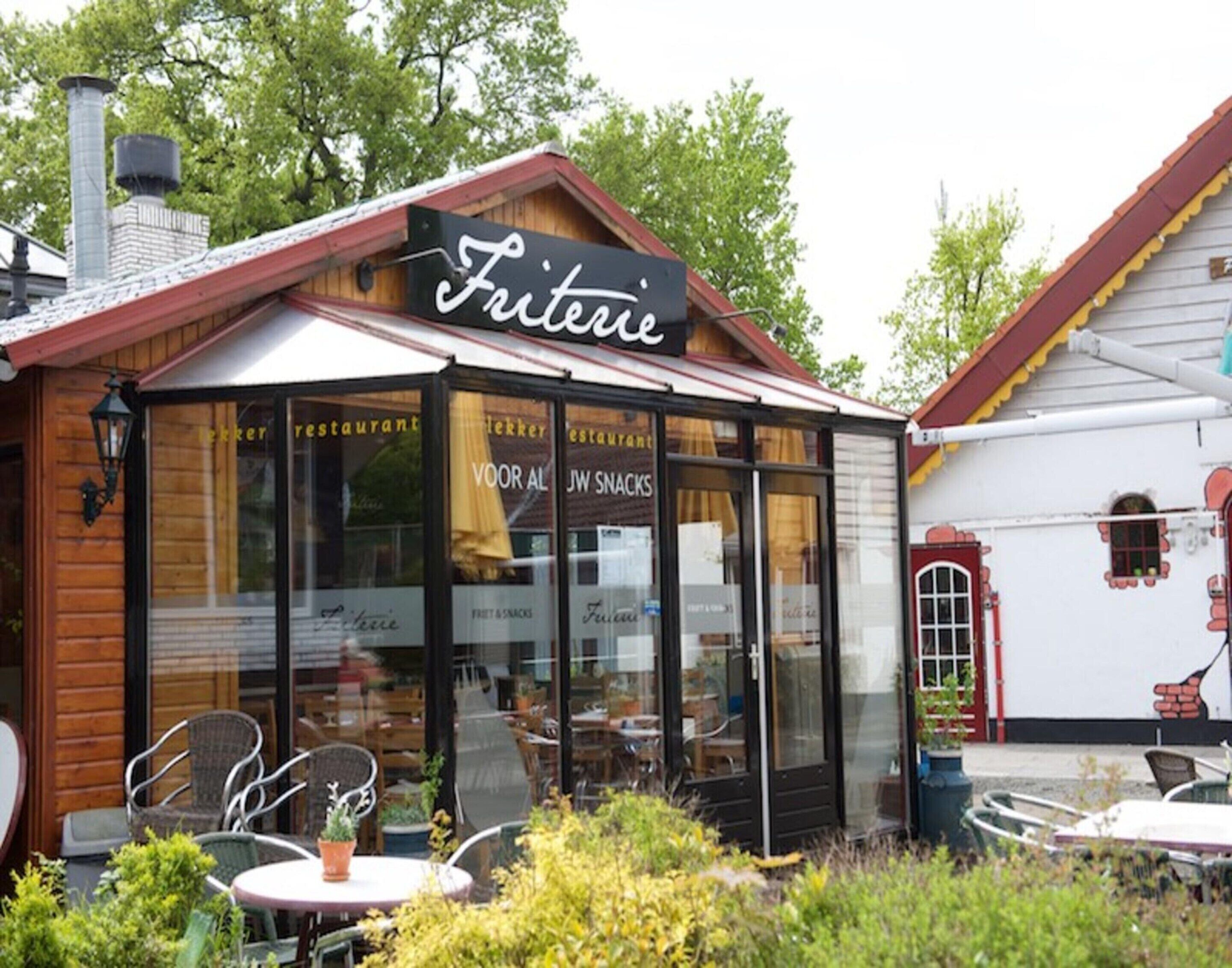 Un restaurante acogedor llamado 'Fritterie' con terraza y fachada de madera rústica.