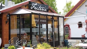 Un restaurante acogedor llamado 'Fritterie' con terraza y fachada de madera rústica.