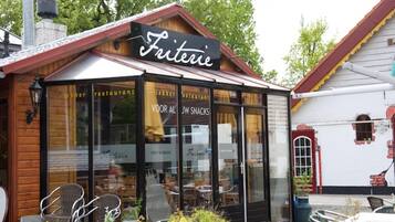 Un restaurante acogedor llamado 'Fritterie' con terraza y fachada de madera rústica.