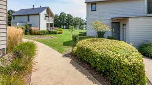 A residential area with two houses, a paved driveway, and well-maintained lawns. - Lakeside Bliss Retreat (Froidchapelle)