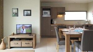 A modern kitchen with wooden cabinets, a microwave, and a dining area with a table and chairs. - Lakeside Bliss Retreat (Froidchapelle)