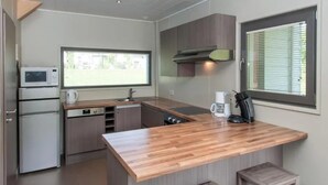 Una cocina moderna con encimera de madera, electrodomésticos de acero inoxidable y una ventana con persianas.