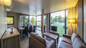 Un salon moderne avec un coin repas, de grandes fenêtres et une vue sur l’extérieur.