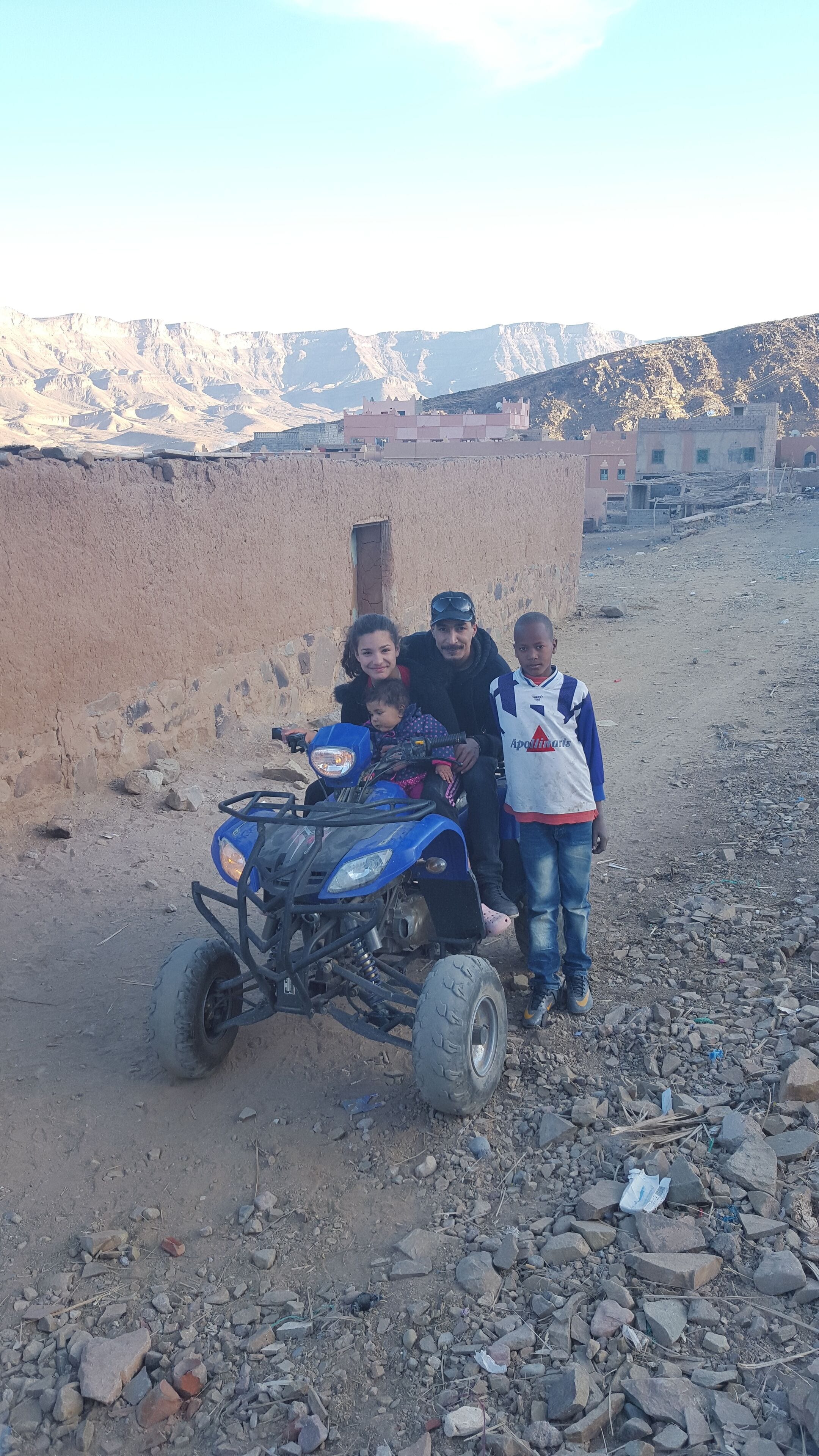 Un grupo de personas con un vehículo todo terreno azul en un entorno rocoso al aire libre.