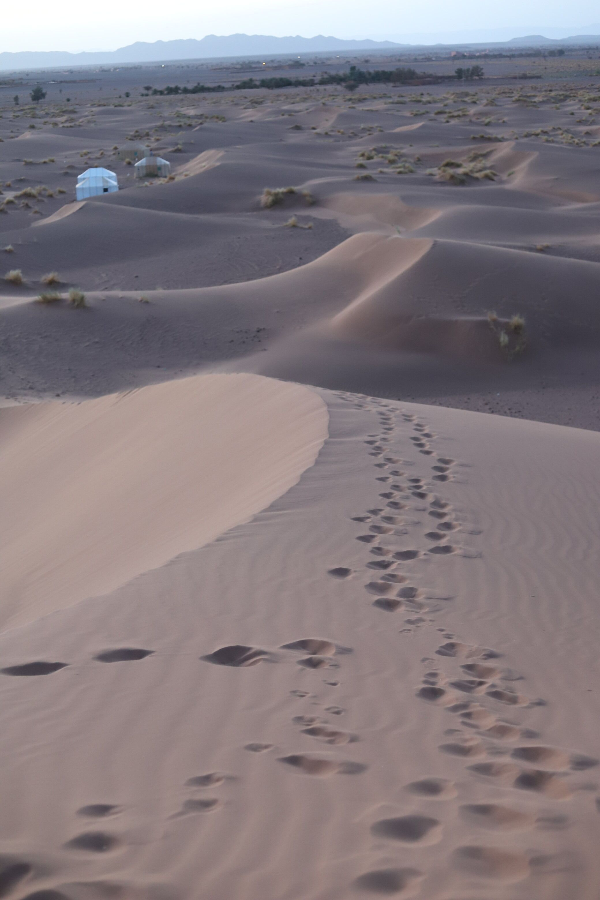 Paisaje desértico con dunas de arena y algunas estructuras pequeñas.
