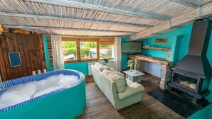 Una habitación acogedora con jacuzzi, sofá, chimenea y vistas al exterior.