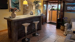 Un rústico área de bar con taburetes de madera, un jarrón grande con flores y una lámpara colgante.