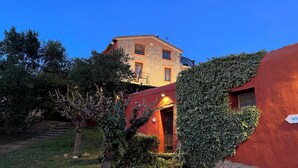Un edificio de piedra con fachada roja, rodeado de vegetación y árboles.