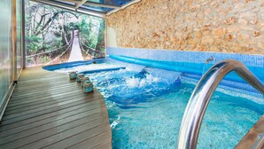 Uma área de spa com um deck de madeira, uma parede de pedra e uma vista para uma ponte suspensa ao fundo.