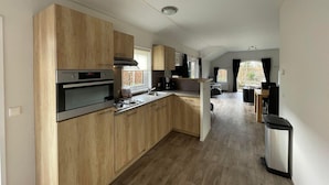 Een moderne keuken met houten kastjes, een gasfornuis en een inbouwoven.