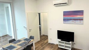 Een moderne kamer met een eethoek, een flatscreen televisie en een airconditioning.