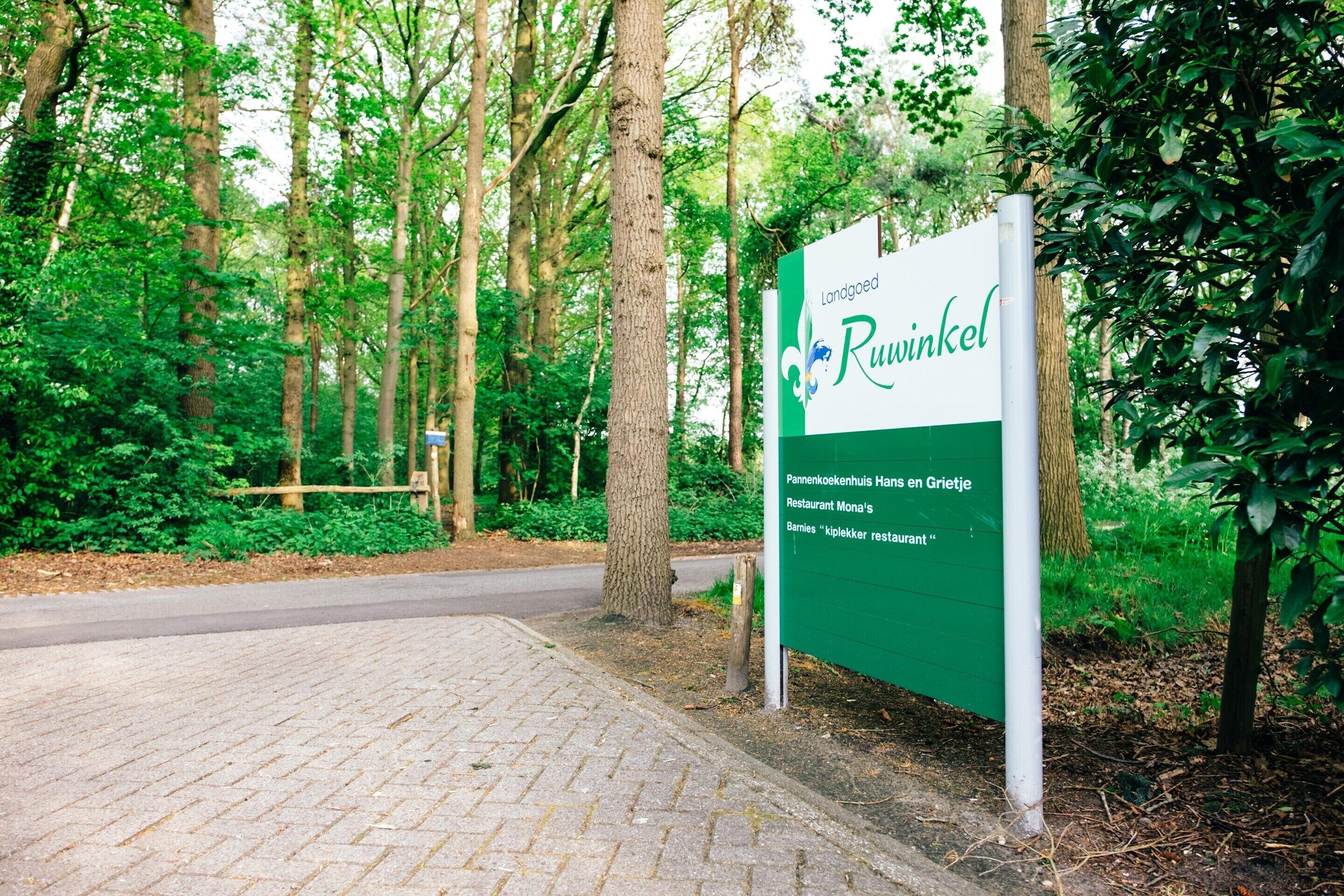 A sign for Landgoed Ruwinkel, indicating a restaurant named "Pannenkoekenhuis Hans en Grietje" and "Bram's 'kipkelker restaurant'".