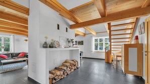 Un salón amplio con chimenea, una escalera de madera y vistas al exterior.