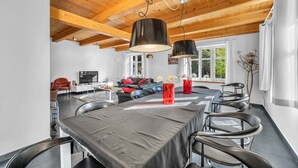 Un comedor moderno con una mesa larga, sillas negras e iluminación colgante.