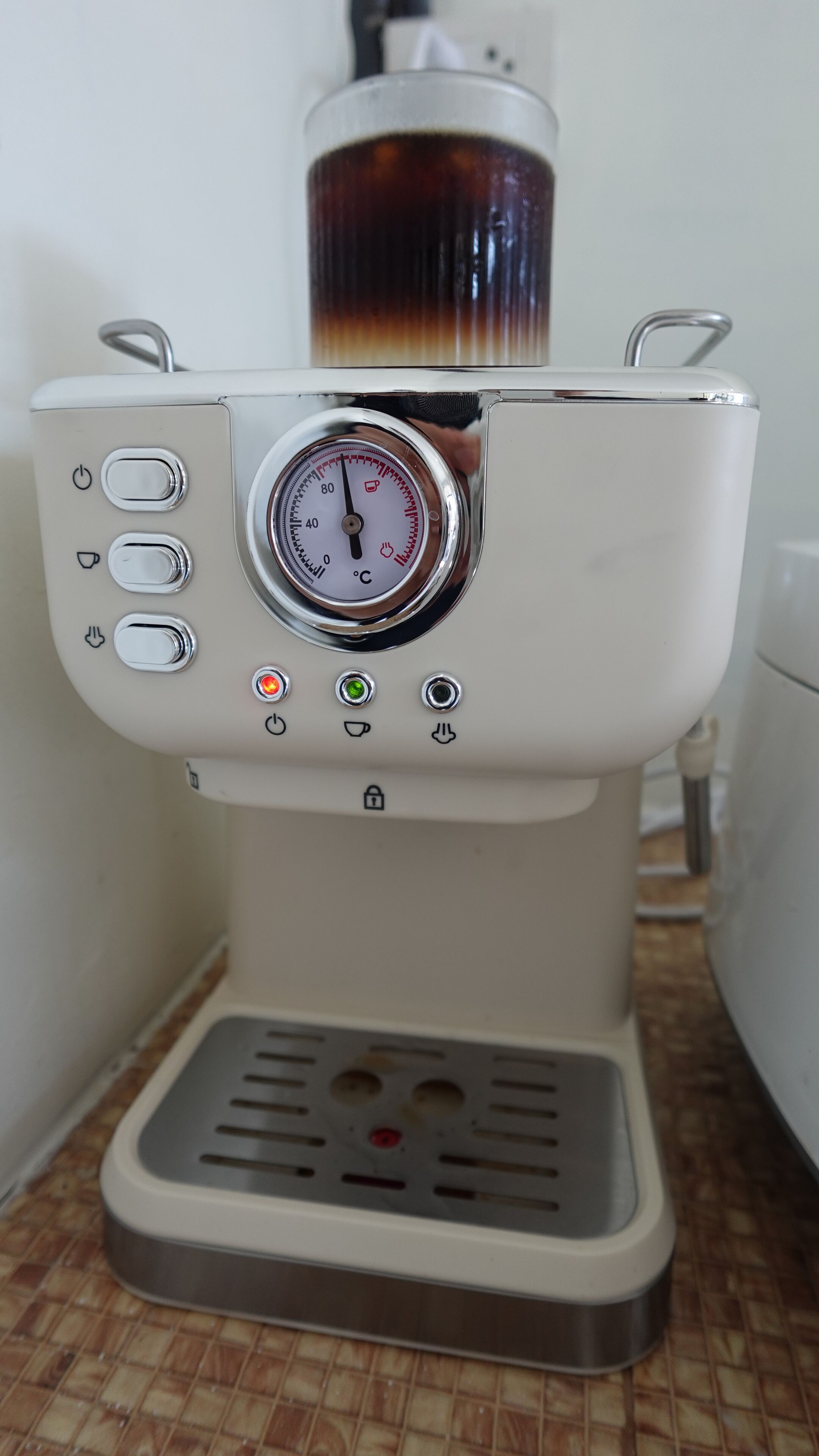 A coffee machine with a digital temperature gauge, control buttons, and a water reservoir.