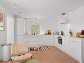 A modern kitchen with white cabinetry, a built-in oven, and a window with a view.