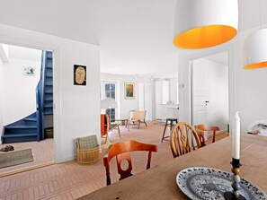 Amplia habitación con una escalera, un comedor con sillas de madera y una gran mesa con un plato decorativo.