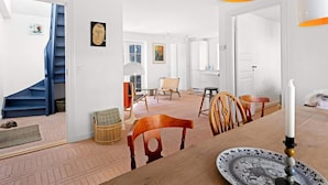 A spacious living area with a staircase, a dining table with chairs, and a large window. - 5 Star Holiday Home in Lokken (Lokken)