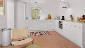 A modern kitchen with white cabinetry, a built-in oven, and a window with a view of the countryside. - 5 Star Holiday Home in Lokken (Lokken)