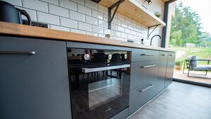 A modern kitchen with a built-in oven, a wooden countertop, and a view of the outdoors. - Apartment Near Pernstejn Castle in Smrcek (Býšovec)