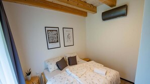 A bedroom with a bed, two framed artworks, a wooden headboard, and a small plant. - Apartment Near Pernstejn Castle in Smrcek (Býšovec)