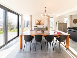 A modern dining area with a large table, black chairs, and a chandelier.