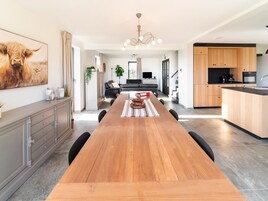 Una cucina moderna con mobili in legno, un'isola centrale e un'area pranzo con un tavolo lungo.