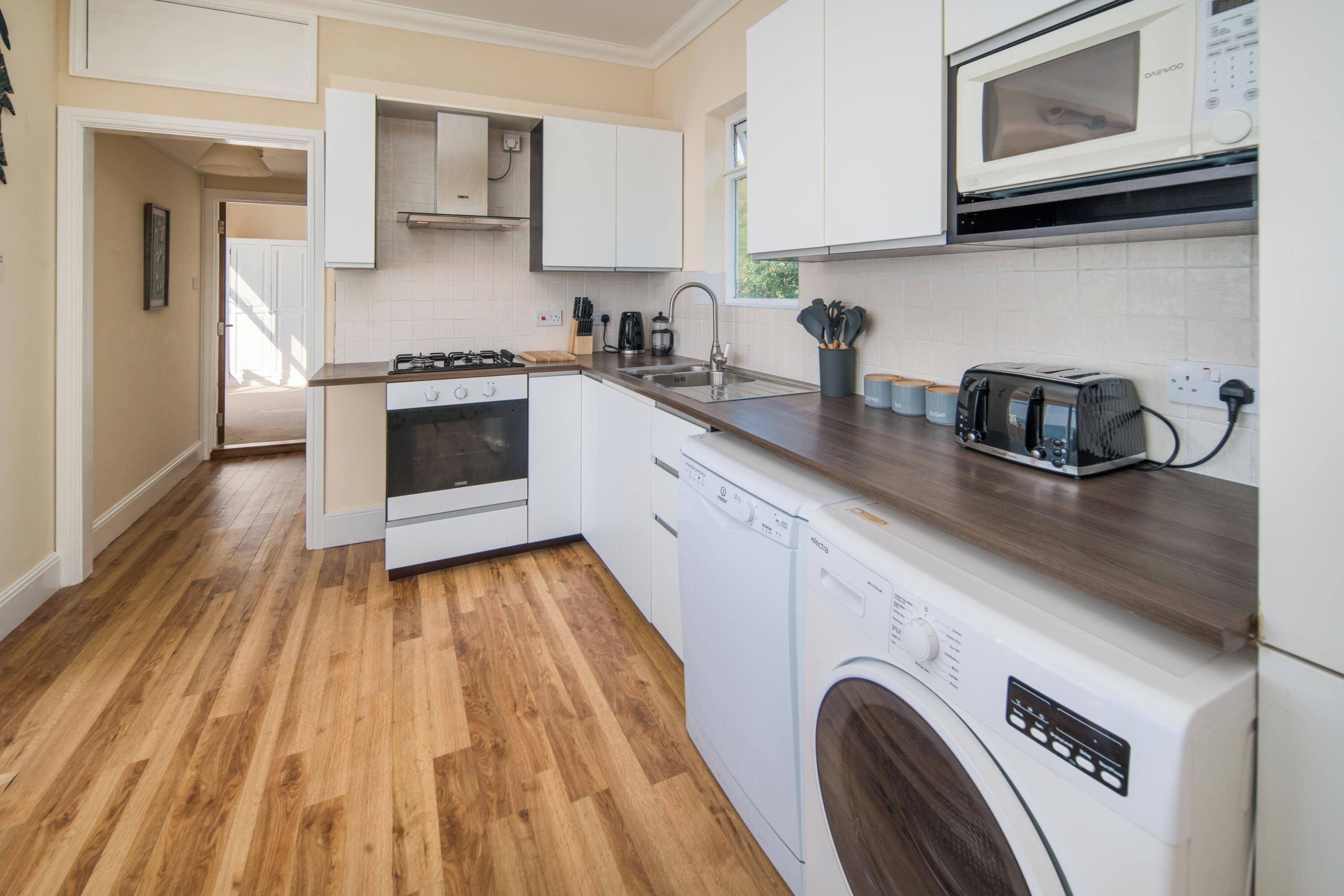 A modern kitchen with white cabinets, a microwave, a toaster, and a dishwasher.