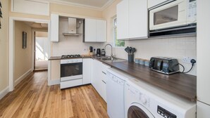 A modern kitchen with white cabinets, a microwave, a toaster, and a dishwasher. - Stunning Penthouse Apartment (Totland Bay)