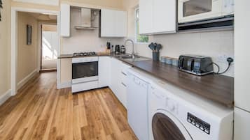 A modern kitchen with white cabinets, a microwave, a toaster, and a dishwasher.