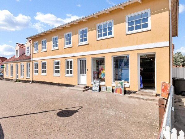 A two-story building with multiple windows and a ground-level entrance. - 5 Star Holiday Home in Lokken (Lokken)