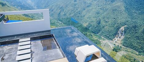 Terraza en la azotea con piso de vidrio, que ofrece vistas a un paisaje montañoso.