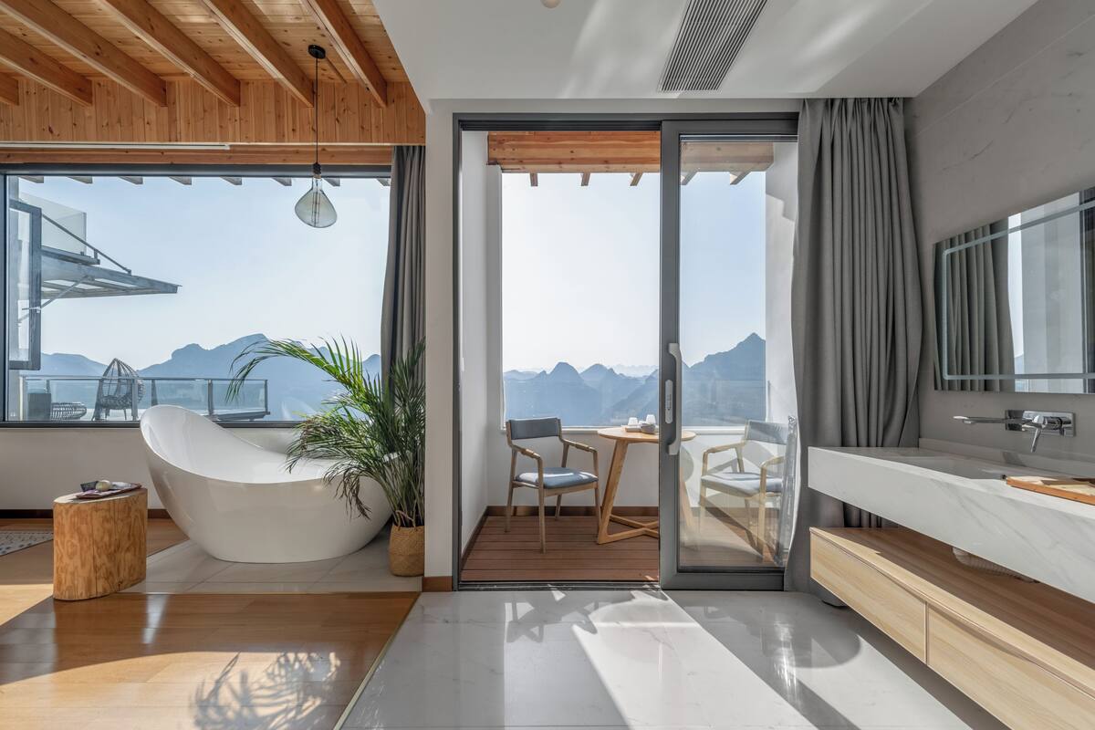 Ein modernes Badezimmer mit einer Badewanne, einem großen Spiegel und Bergblick.
