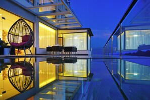Un edificio moderno con facciata in vetro, piscina e area salotto all'aperto.