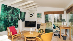 A modern living room with a large TV, wooden furniture, and artwork on the walls. - 4 Person Holiday Home in Frederiksvaerk (Frederiksvaerk)