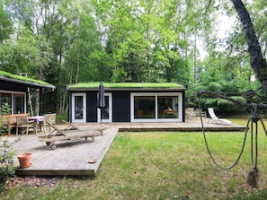 A cabin with a deck, a covered outdoor seating area, and a rope swing. - 4 Person Holiday Home in Frederiksvaerk (Frederiksvaerk)