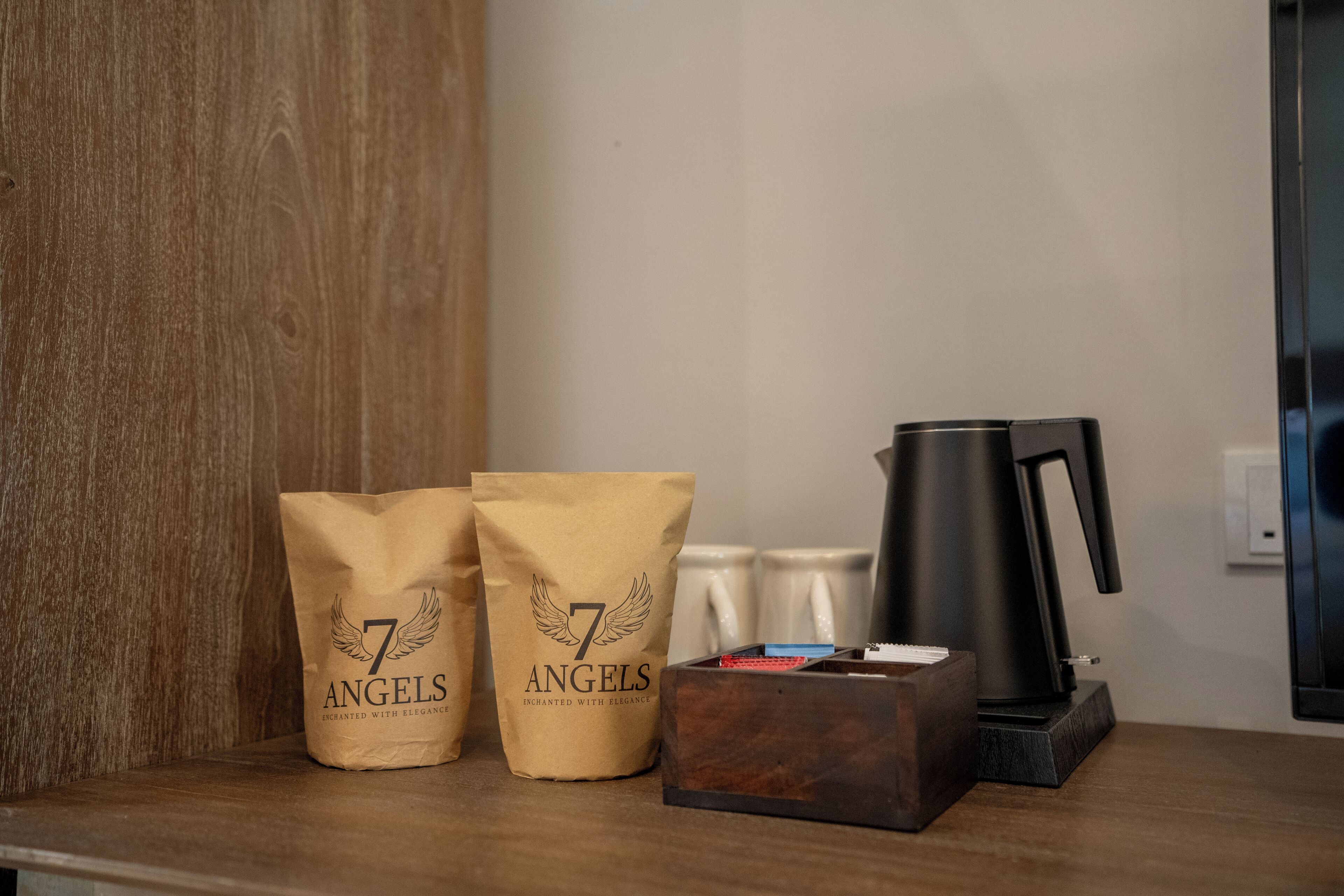 A wooden shelf with two brown paper bags labeled "7 Angels," a black coffee maker, and a wooden box.