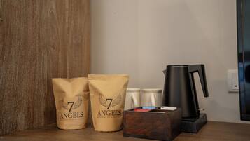 A wooden shelf with two brown paper bags labeled "7 Angels," a black coffee maker, and a wooden box.