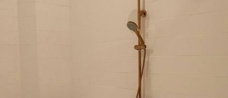 Una bañera tipo pata de león con cabezal y manguera de ducha.