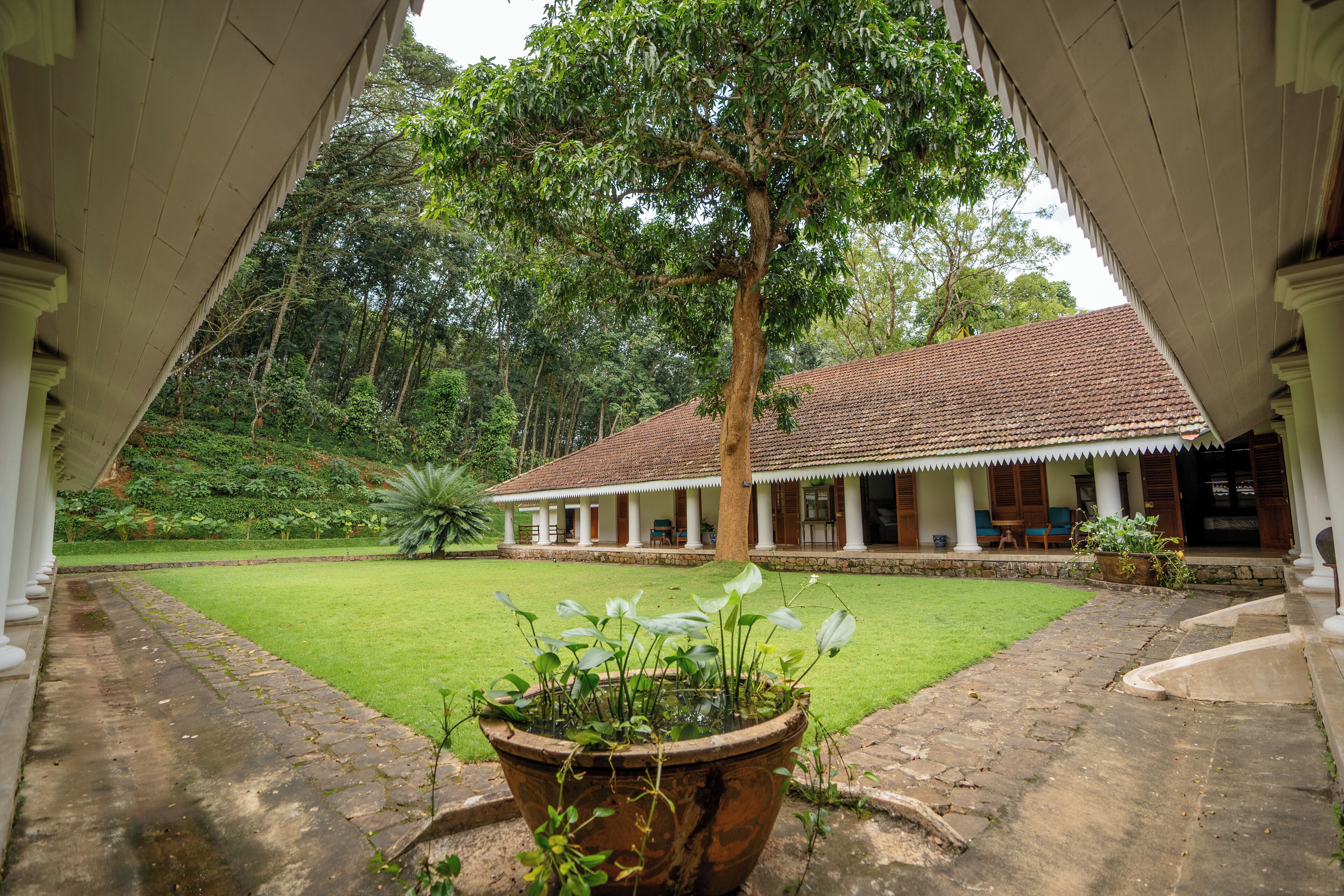 A traditional building with a tiled roof, surrounded by a well-maintained lawn and a large tree.