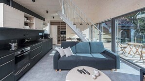 A modern interior with a black sofa, a coffee table, and a staircase leading to an outdoor area. - Villa in Bedrichov Near Ski Slopes (Bedrichov)