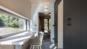 A modern interior with a long, narrow room featuring a window, a table, and a chair. There is a dark-colored cabinet on the right and a door leading to another room. - Villa in Bedrichov Near Ski Slopes (Bedrichov)