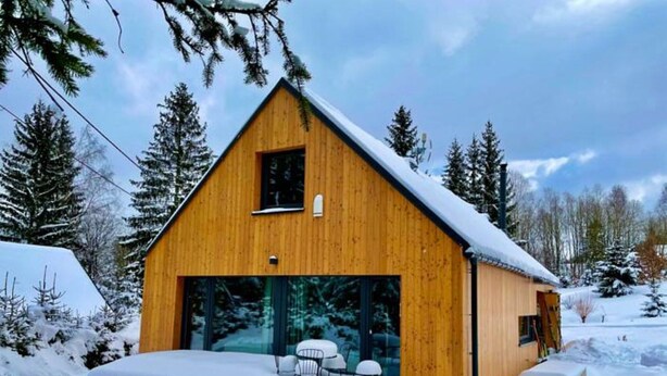 A wooden cabin with a large glass door and windows, surrounded by snow-covered trees. - Villa in Bedrichov Near Ski Slopes (Bedrichov)