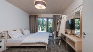 A bedroom with a bed, a desk with a chair, a TV, and a window with curtains. - Villa in Bedrichov Near Ski Slopes (Bedrichov)