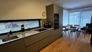 Eine moderne Küche mit Einbauofen, Kaffeemaschine und einem Fenster mit Jalousien.
